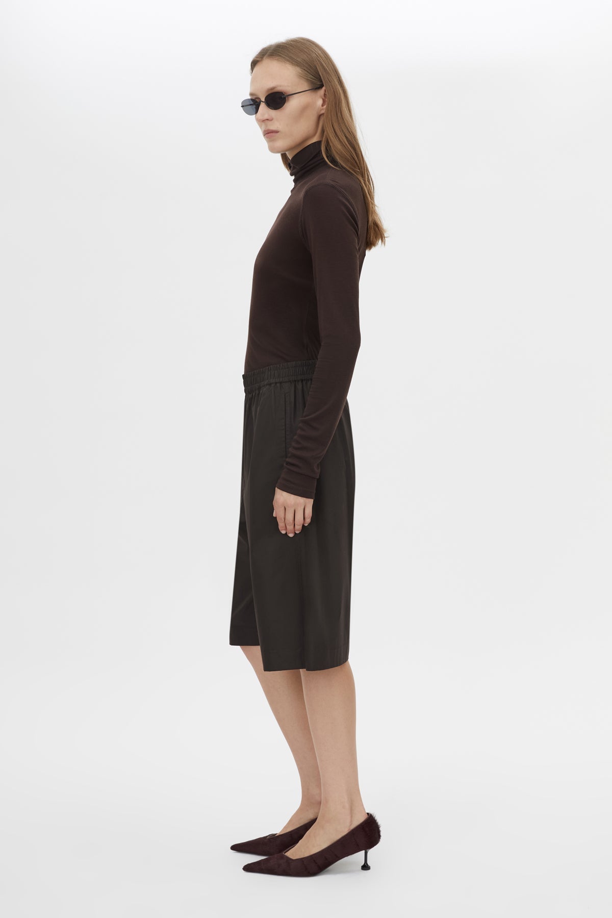 Side view CAMILLA AND MARC Barre High Neck Top in Chocolate with long sleeves and turtleneck silhouette.  
