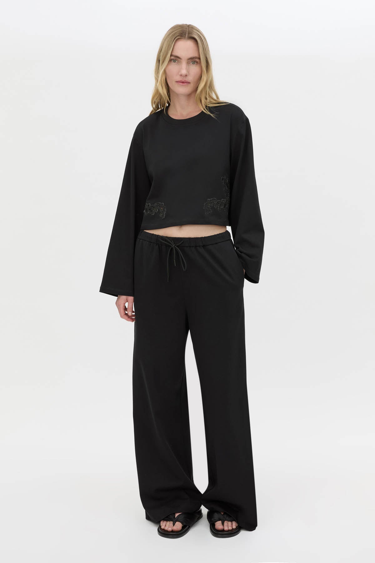 Front-styled view CAMILLA AND MARC Niami Crochet Cropped Top in black with cut‑away crochet detailing at hem.